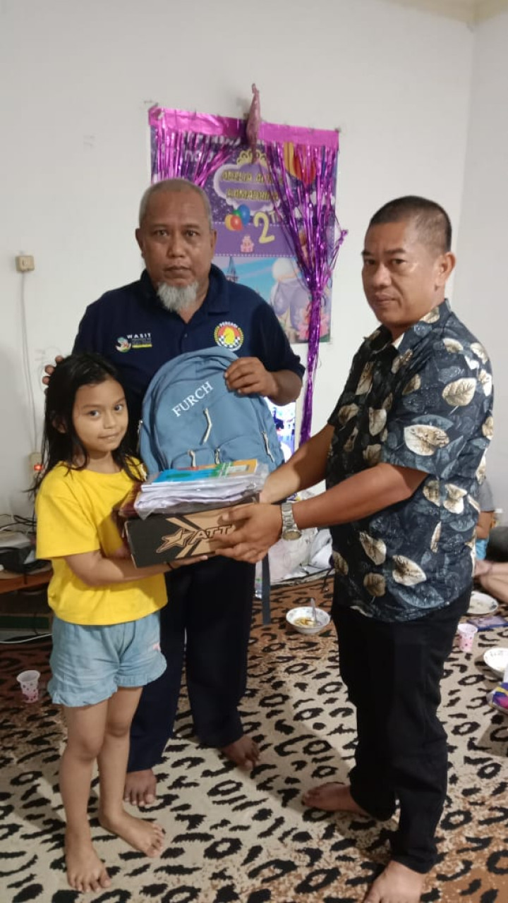 Mewakili pimpinan, penyerahan secara simbolis bantuan seragam dan peralatan sekolah warga RT. 022