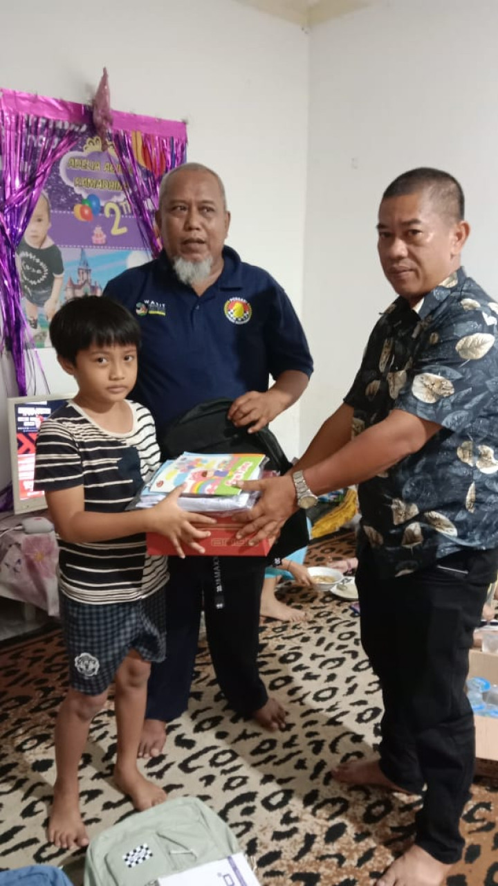 Mewakili pimpinan, penyerahan secara simbolis bantuan seragam dan peralatan sekolah warga RT. 022